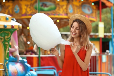 Happy young woman with cotton candy in amusement park