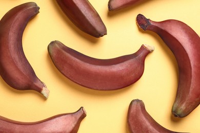 Tasty red baby bananas on yellow background, flat lay