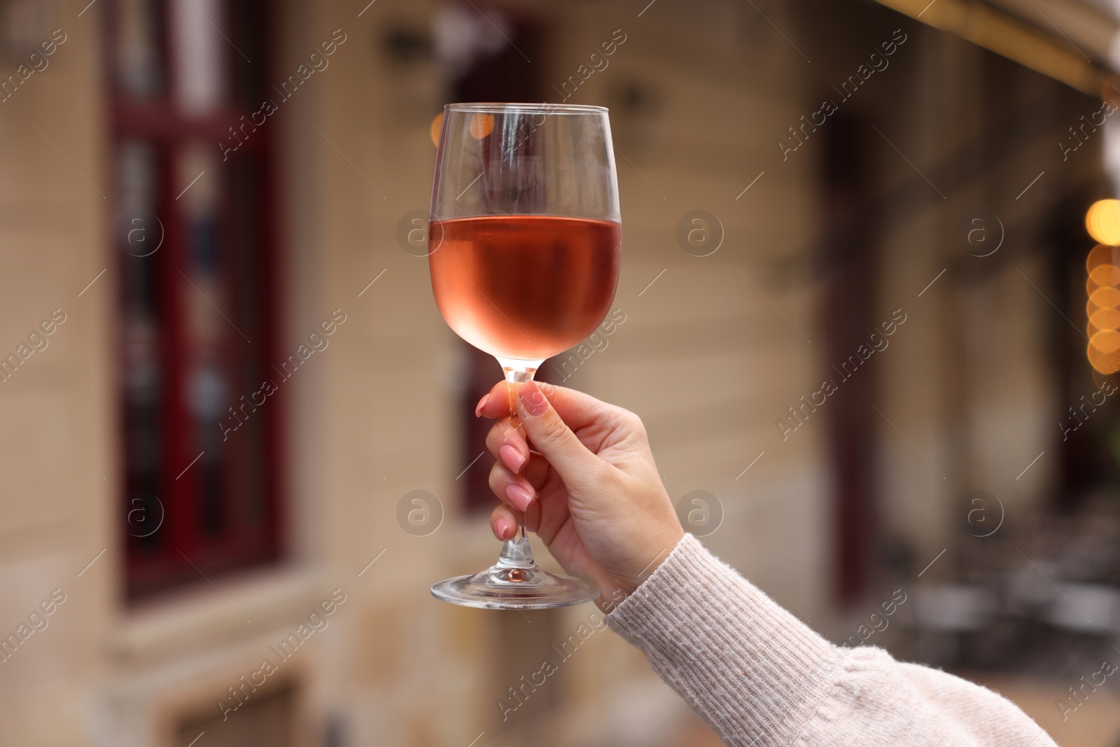 Photo of Woman holding glass of rose wine outdoors, closeup