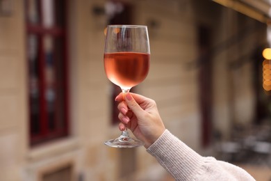 Woman holding glass of rose wine outdoors, closeup