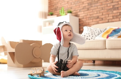 Adorable little child playing with binoculars at home