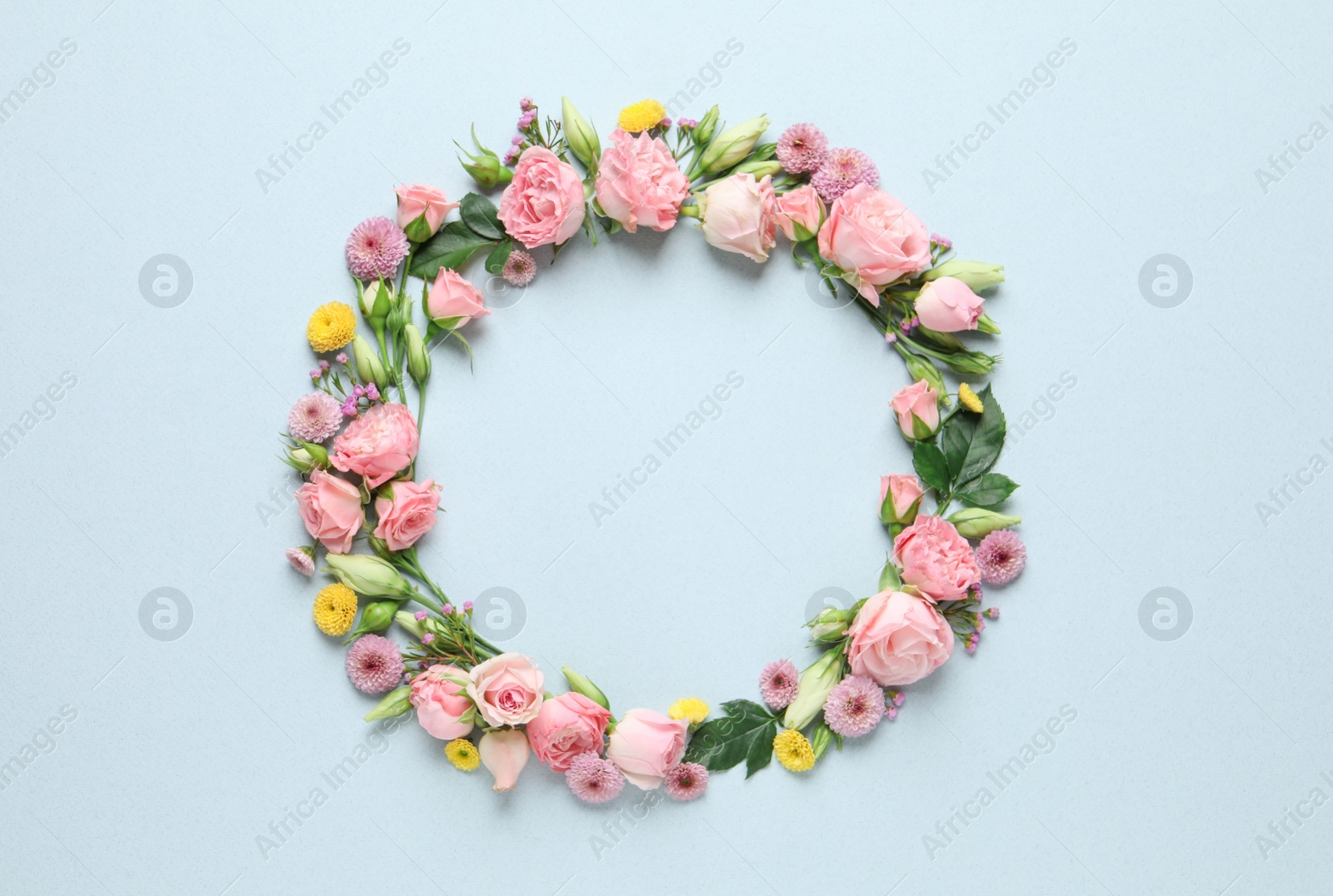 Photo of Wreath made of beautiful flowers and green leaves on light background, flat lay. Space for text