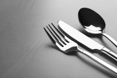 Photo of Shiny cutlery on grey table, closeup. Space for text