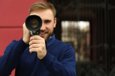 Photo of Young man using vintage video camera outdoors, focus on lens. Space for text