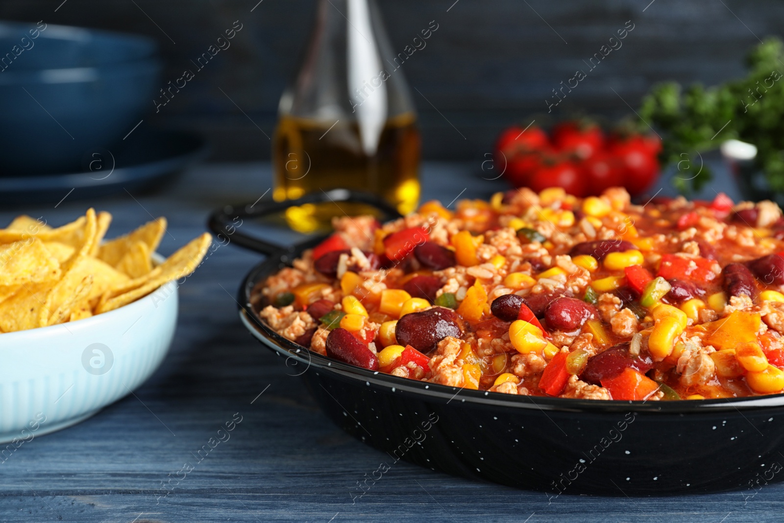 Photo of Pan with tasty chili con carne served on wooden table