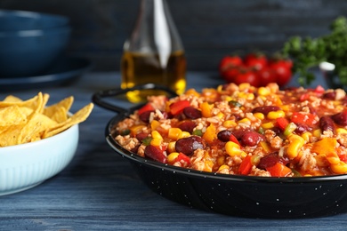 Pan with tasty chili con carne served on wooden table