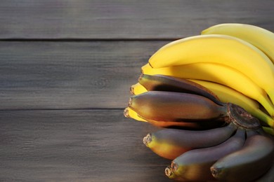 Tasty purple and yellow bananas on wooden table, space for text