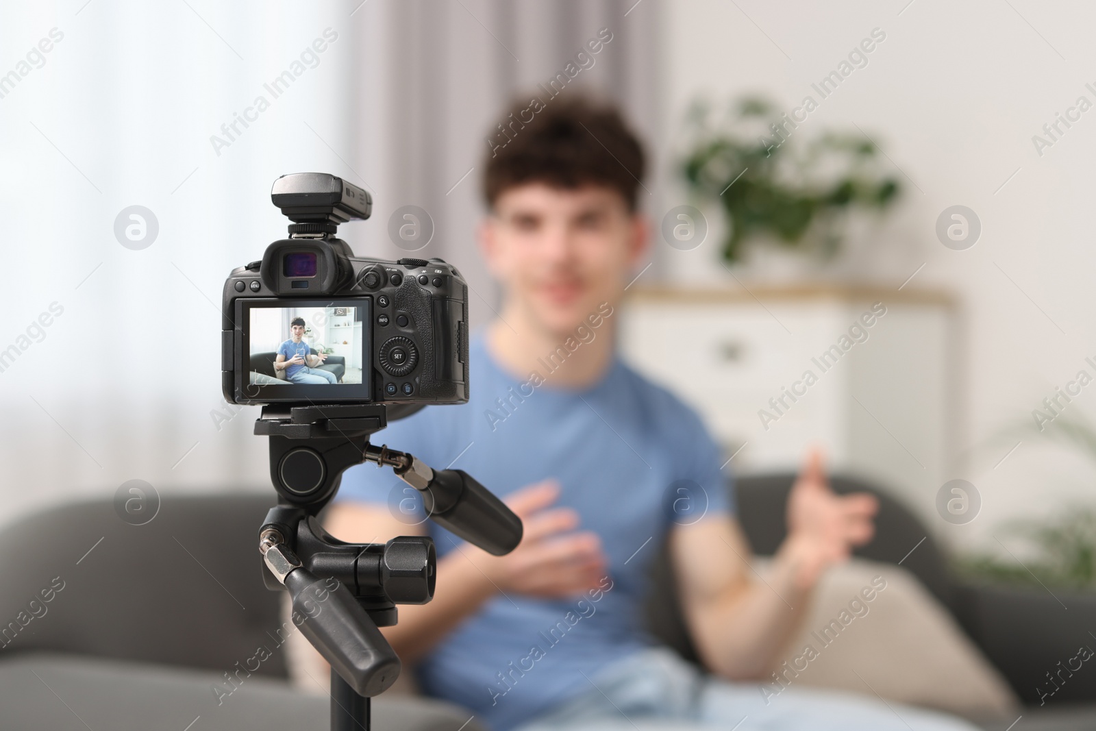 Photo of Teenage blogger explaining something while streaming at home, focus on camera