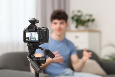 Photo of Teenage blogger explaining something while streaming at home, focus on camera