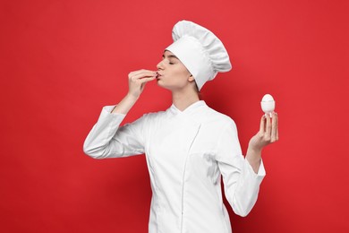 Professional chef holding egg and showing perfect sign on red background