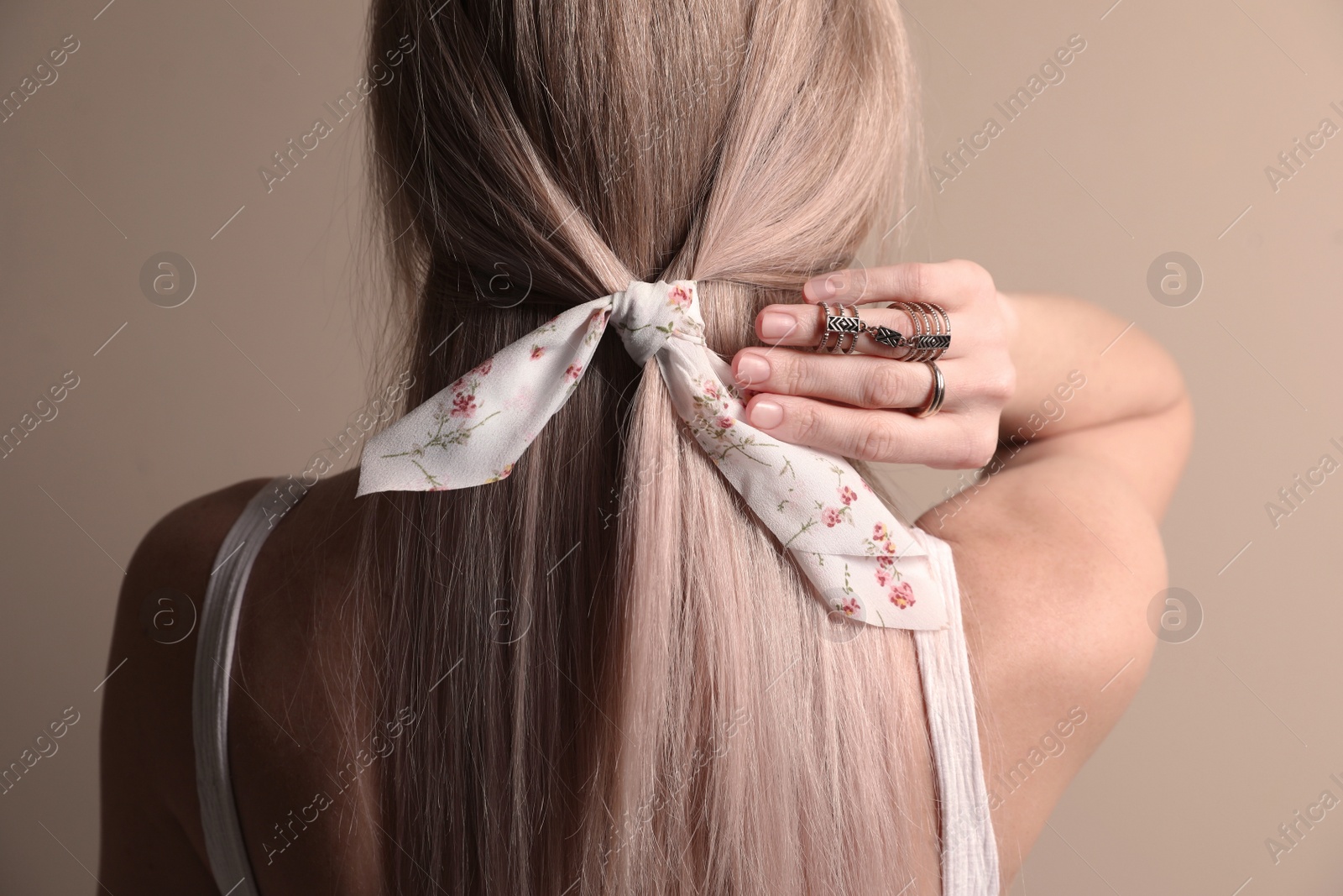 Photo of Young woman with stylish bandana on beige background, back view