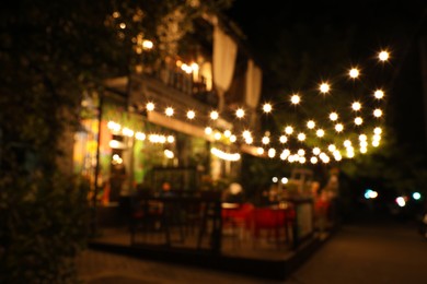 Blurred view of modern cafe with outdoor terrace at night
