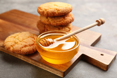 Photo of Tasty honey and cookies on light grey table