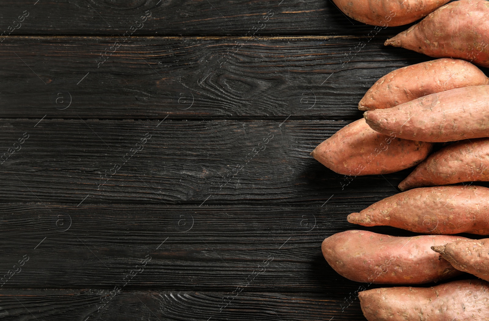 Photo of Flat lay composition with sweet potatoes and space for text on wooden background