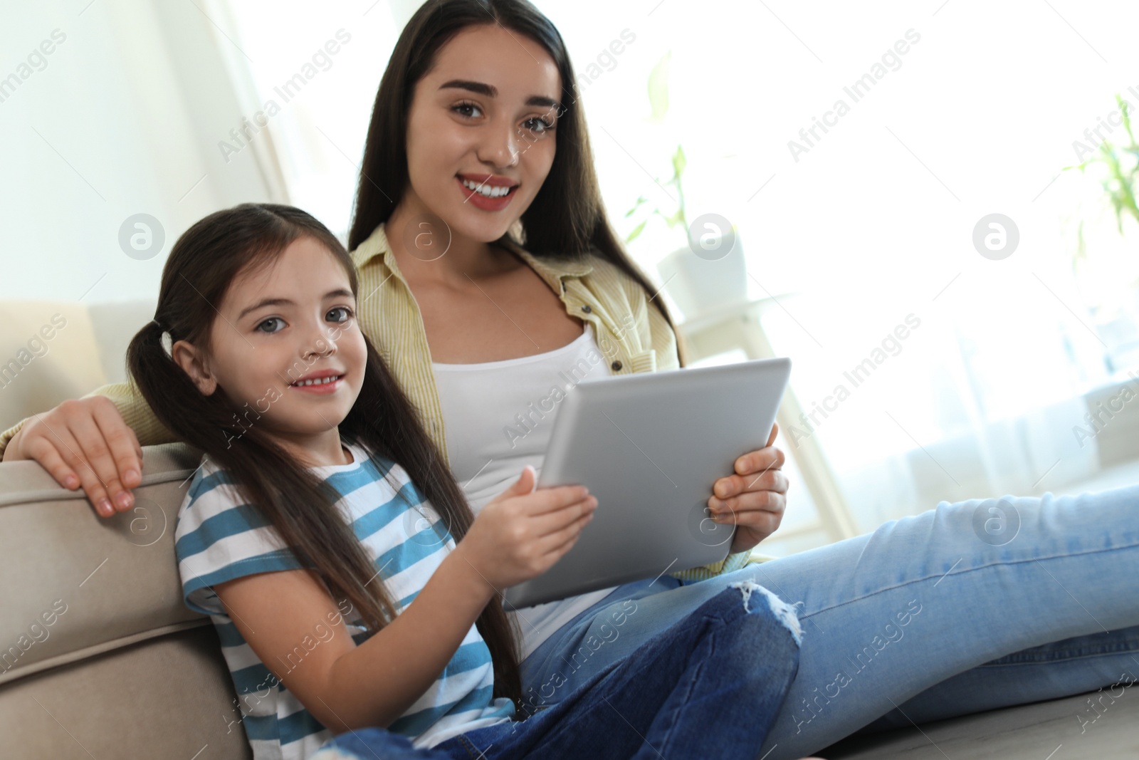 Photo of Mother and daughter reading E-book together at home