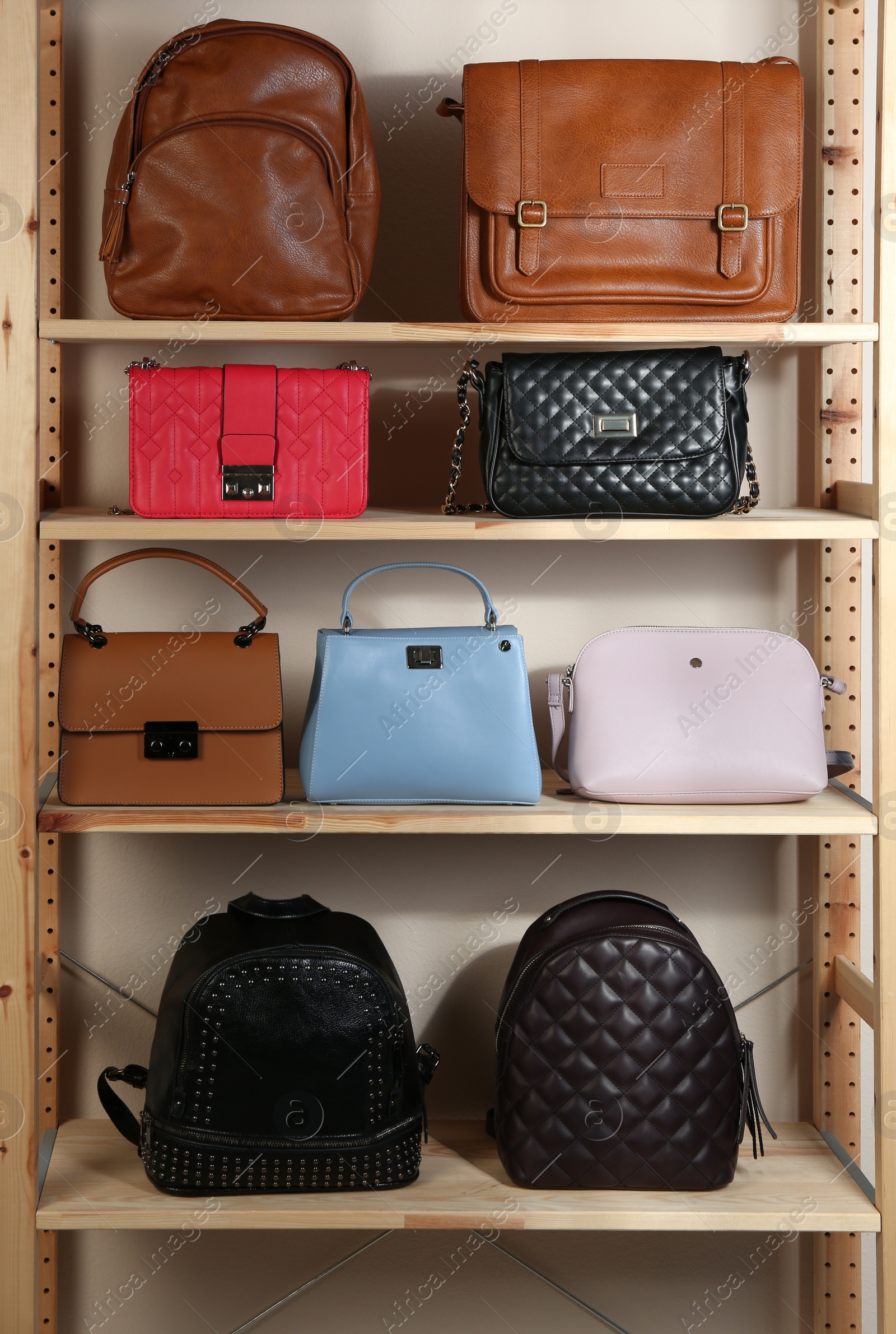 Photo of Collection of stylish leather bags on wooden shelving unit