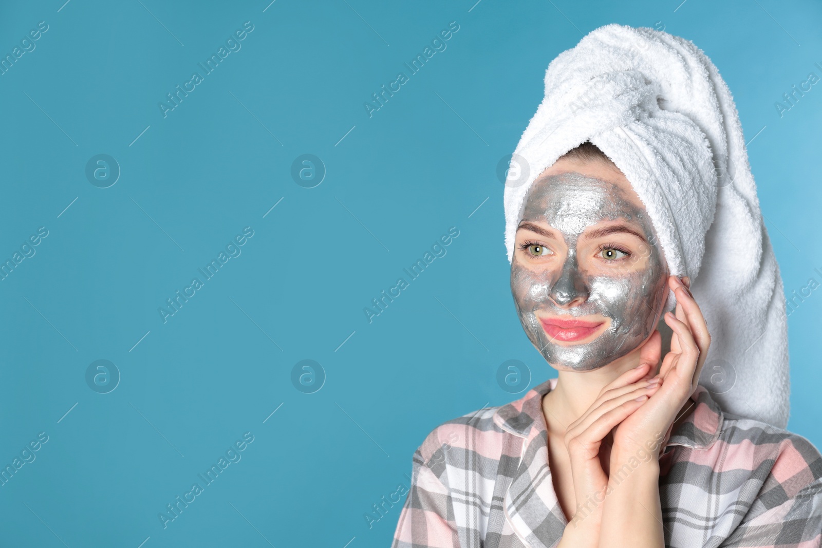 Photo of Young woman with cleansing mask on her face against color background, space for text. Skin care