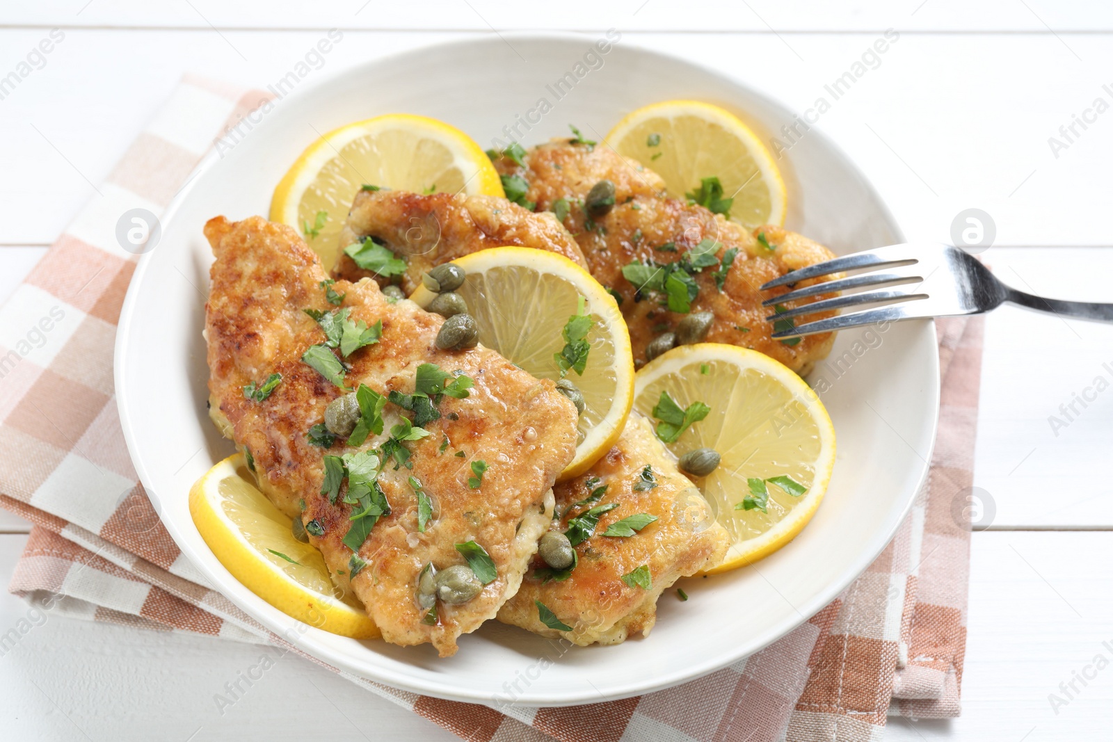 Photo of Delicious chicken piccata served on white wooden table