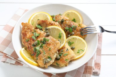 Delicious chicken piccata served on white wooden table