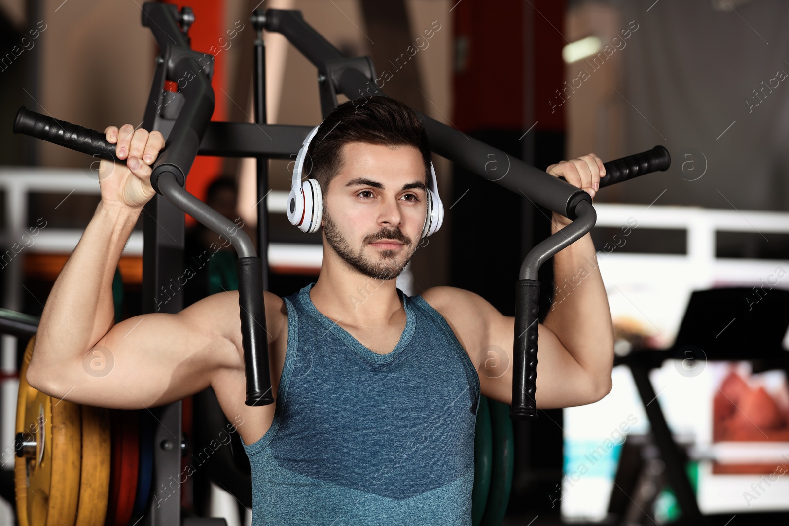 Photo of Young man with headphones listening to music and working out at gym