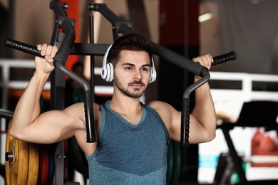 Young man with headphones listening to music and working out at gym