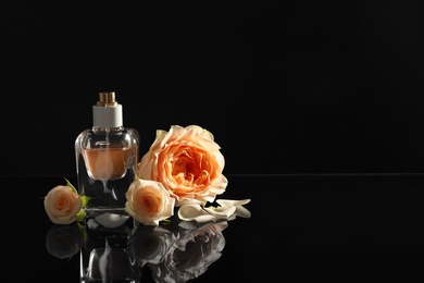 Elegant bottle of perfume and beautiful flowers on black background. Space for text