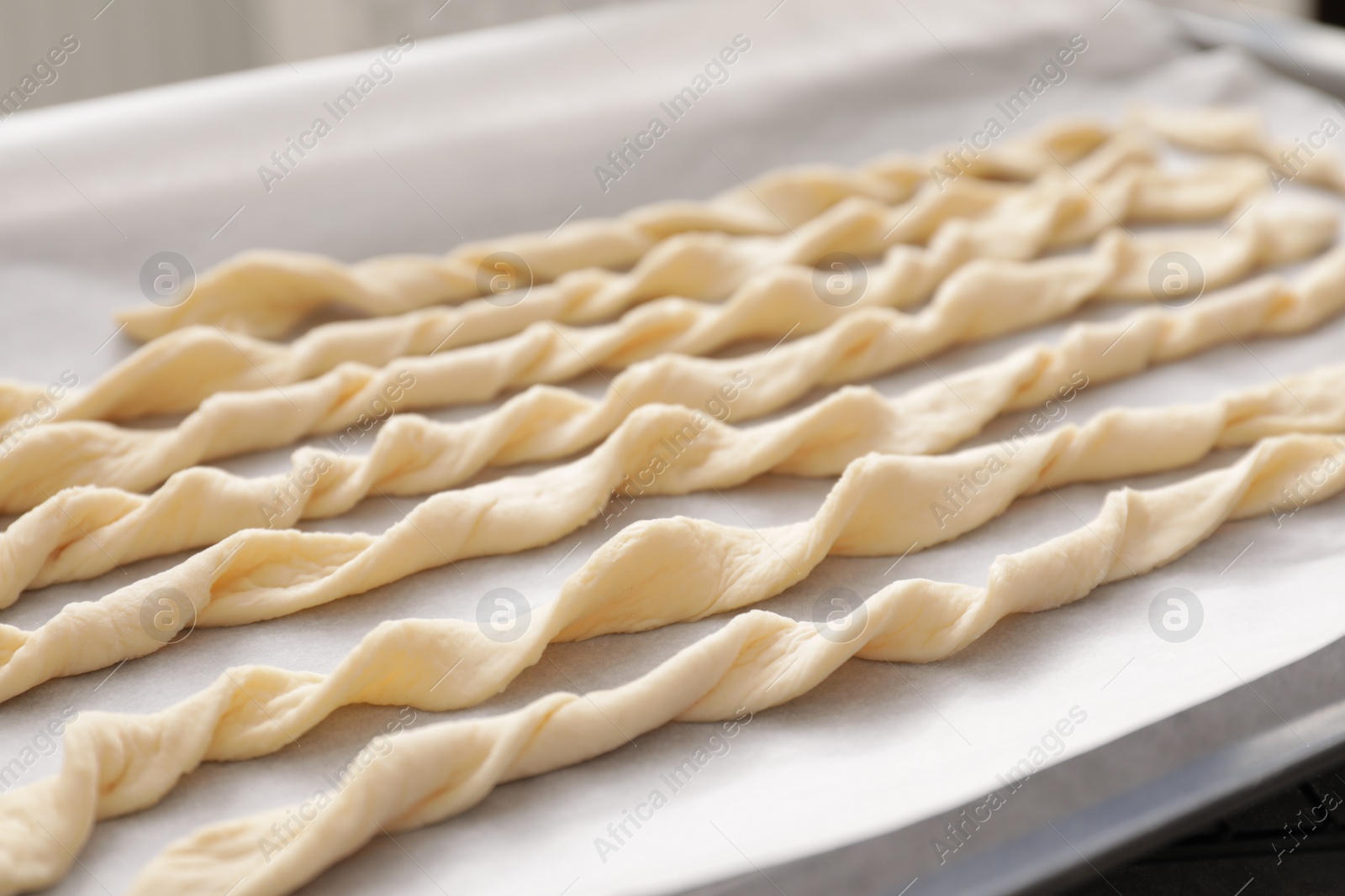 Photo of Homemade breadsticks on baking sheet, closeup. Cooking traditional grissini