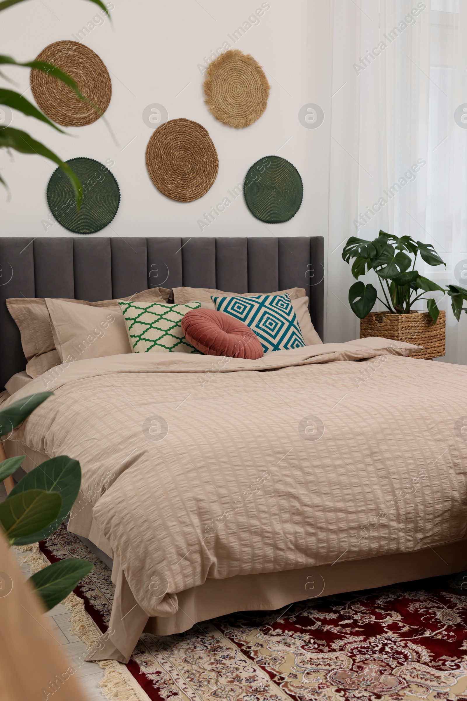 Photo of Large comfortable bed and potted houseplants in stylish bedroom. Interior design