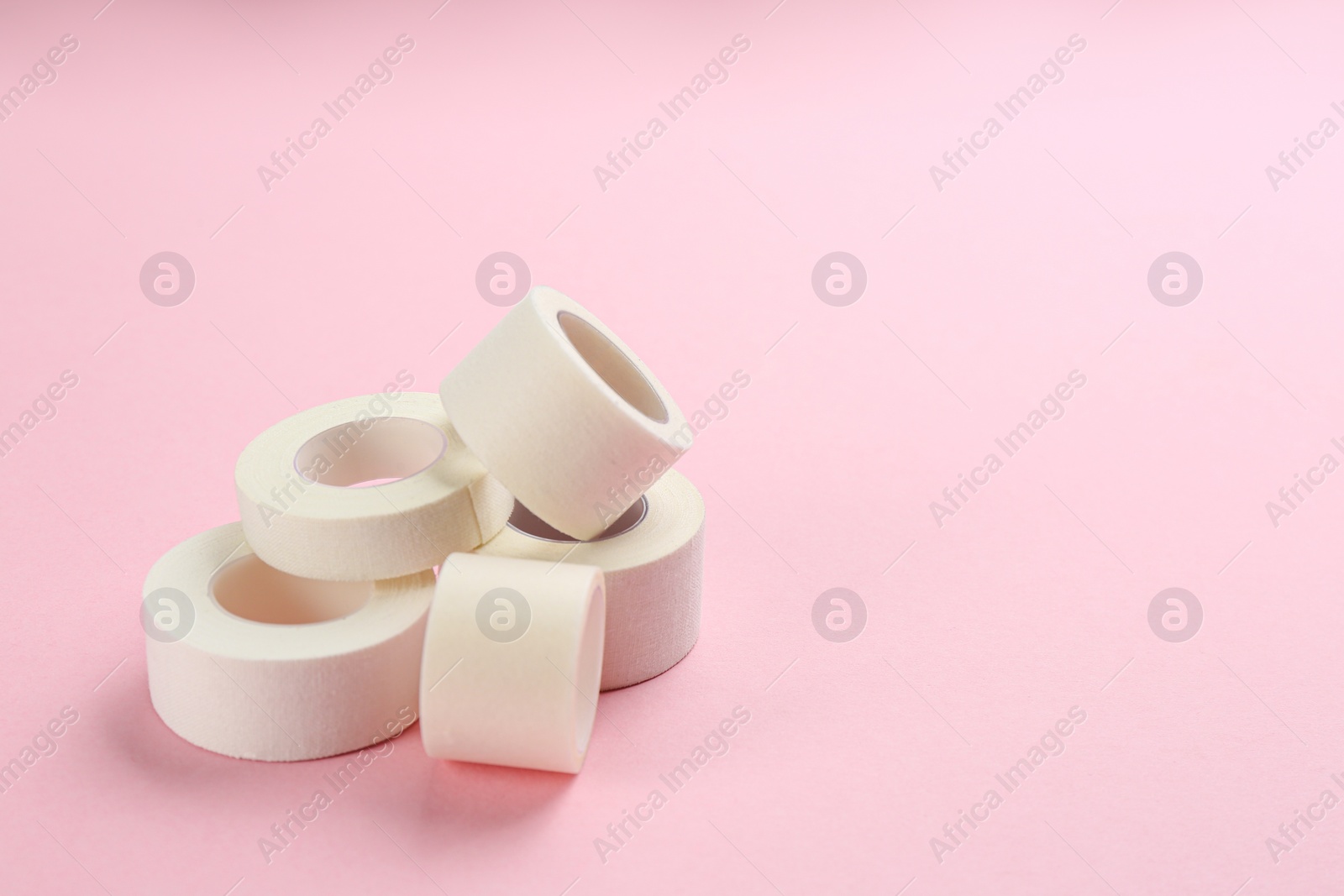 Photo of Sticking plaster rolls on pink background. Space for text