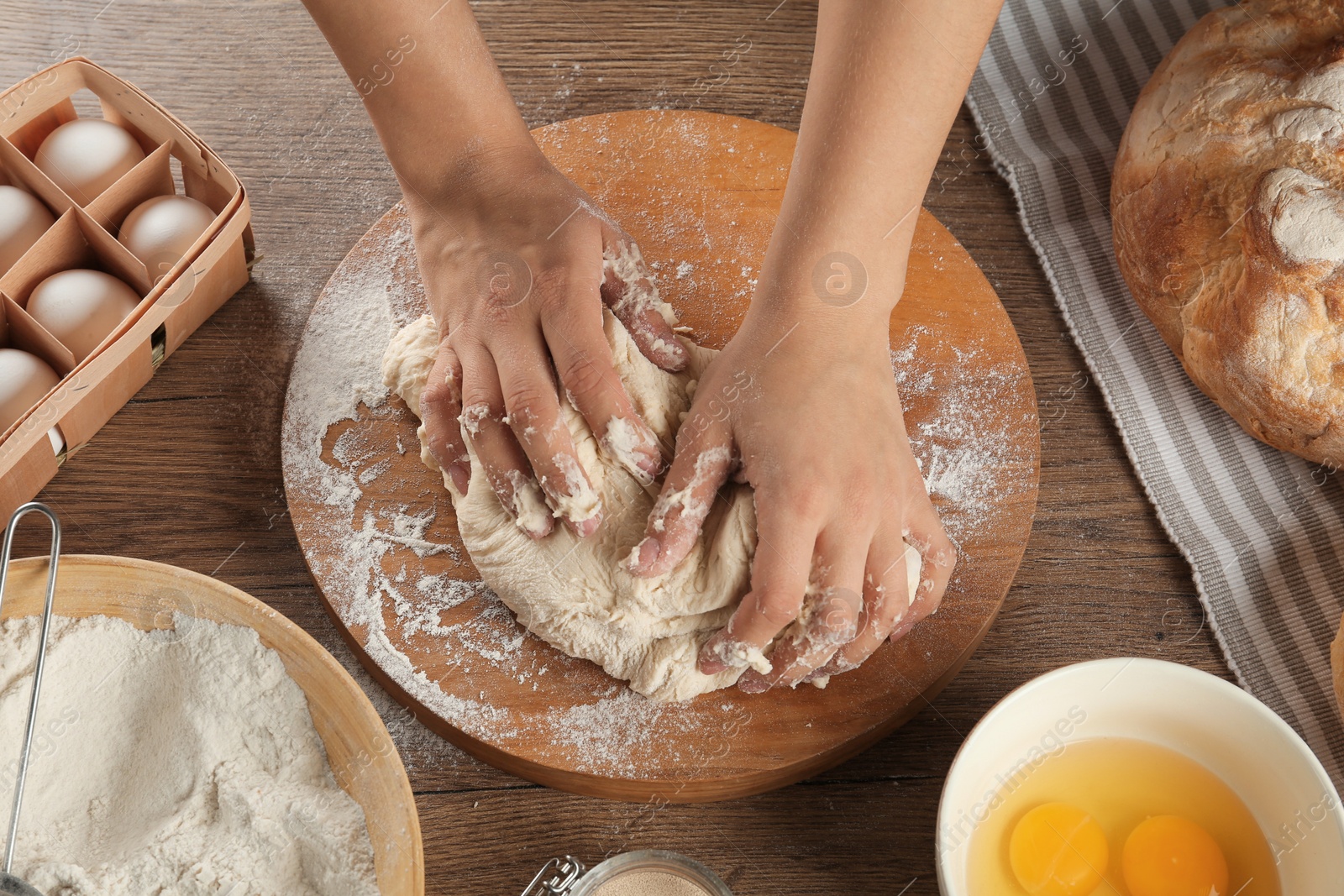 Photo of Female baker preparing bread dough at kitchen table, above view