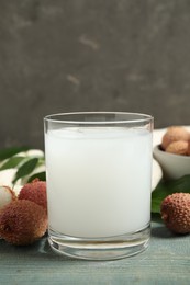 Photo of Fresh lychee juice and fruits on blue wooden table