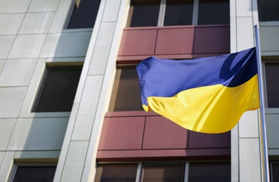 Photo of Ukrainian flag near modern building, low angle view