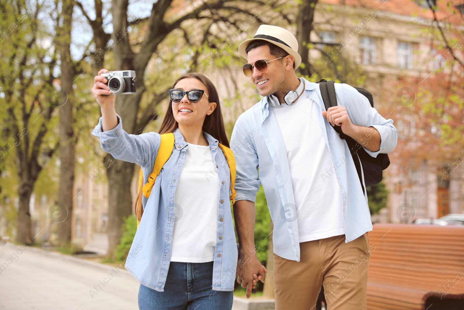 Photo of Happy couple of tourists with camera on city street