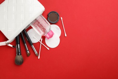 Photo of Cotton pads, swabs, brushes and micellar cleansing water on red background, flat lay. Space for text