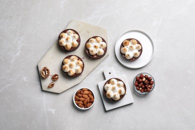Photo of Delicious salted caramel meringue tarts and nuts on light grey marble table, flat lay