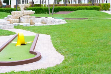 Photo of Green lawn with fresh grass, mini golf course and fountain outdoors