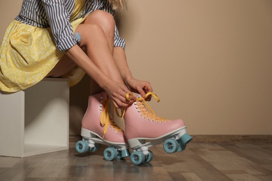 Photo of Young woman with retro roller skates against color wall, closeup. Space for text