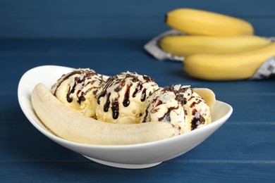 Photo of Delicious banana split ice cream on blue wooden table