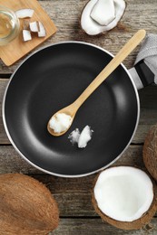 Photo of Flat lay composition with frying pan and organic coconut cooking oil on wooden table