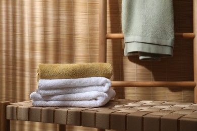 Stacked soft towels on wicker bench indoors, space for text