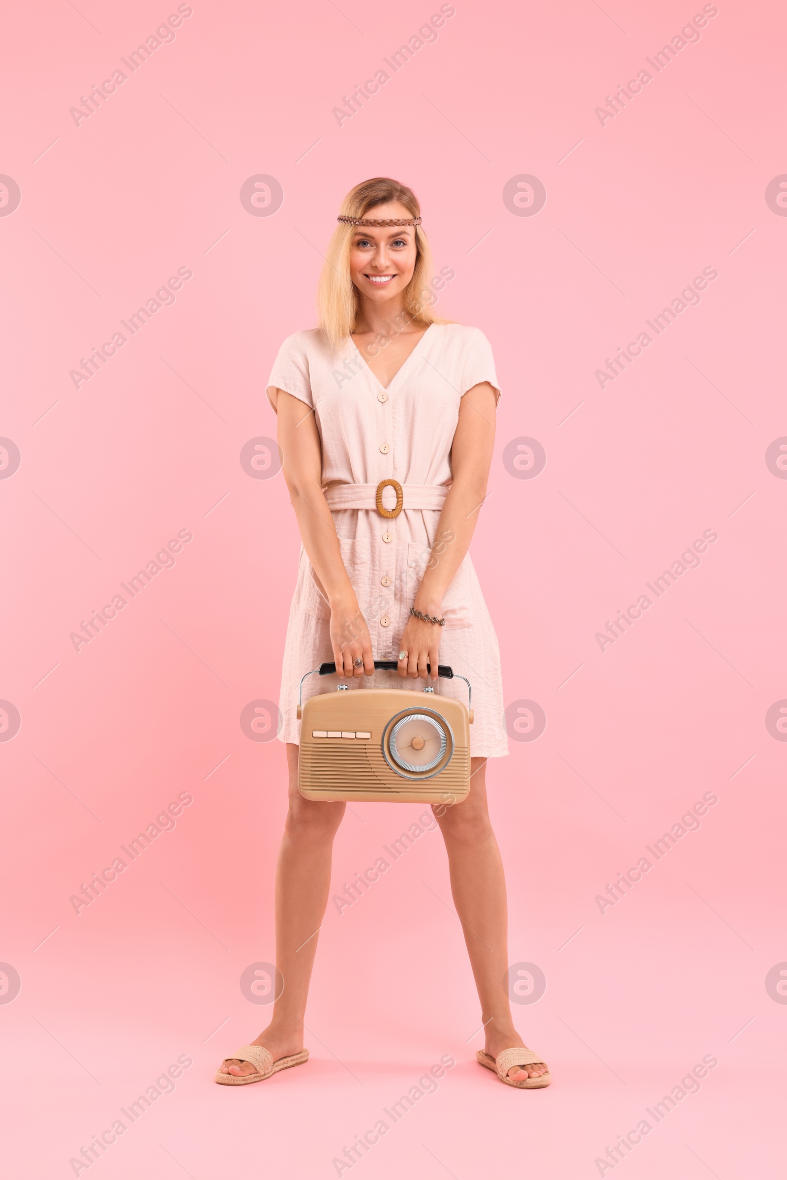 Photo of Happy hippie woman with retro radio receiver on pink background