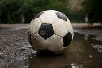 Photo of Dirty soccer ball in muddy puddle outdoors