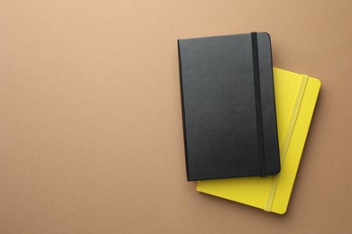 Photo of Different notebooks on light brown background, top view. Space for text