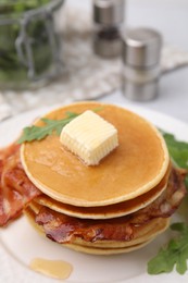 Photo of Delicious pancakes with bacon, butter and arugula on table, closeup