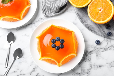 Photo of Delicious fresh jelly with orange slices and blueberries on marble table, flat lay