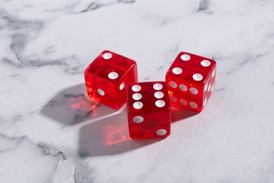 Three red game dices on white marble table