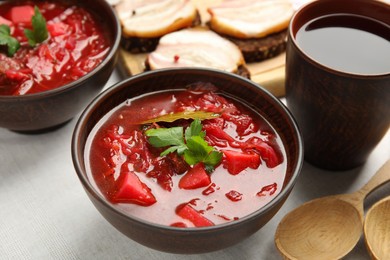 Photo of Stylish brown clay bowl with Ukrainian borsch served on white tablecloth