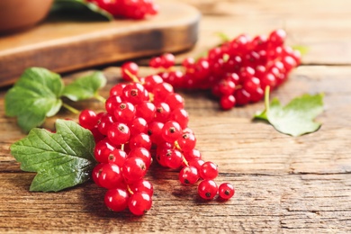 Photo of Delicious red currants and leaves on wooden table, closeup