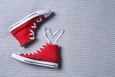 Pair of new stylish red sneakers on light grey fabric, flat lay. Space for text