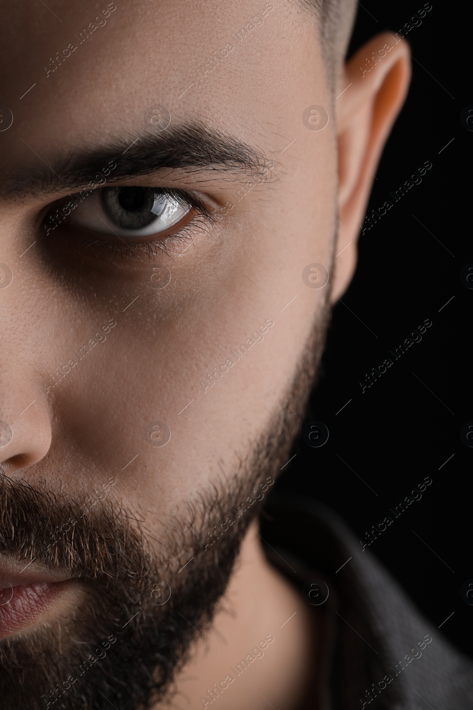 Photo of Evil eye. Man with scary eyes on black background, closeup